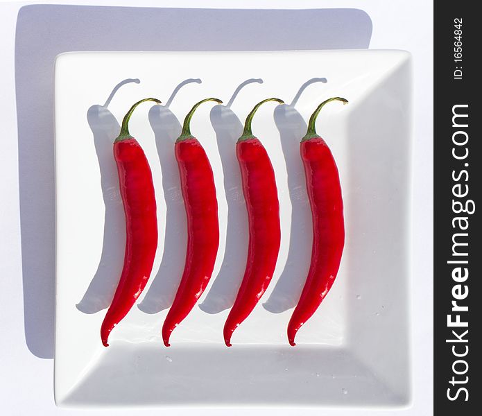 Four identical chillies of square plate. Four identical chillies of square plate