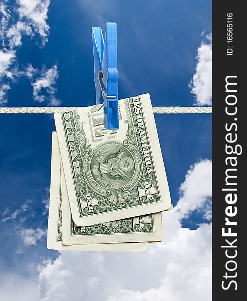 U.s. dollar on rope with clothespin over blue sky. U.s. dollar on rope with clothespin over blue sky