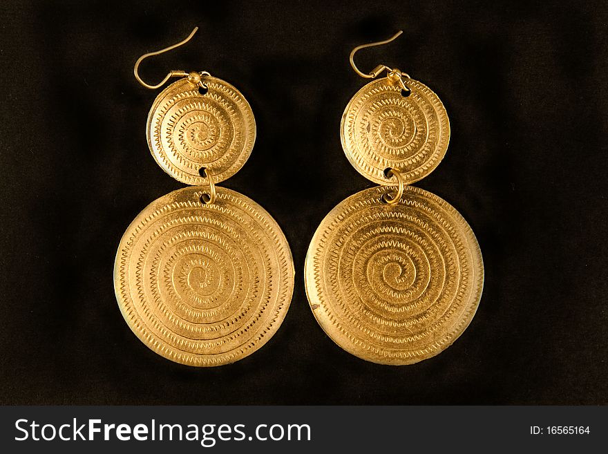 Pair of golden earrings placed on black