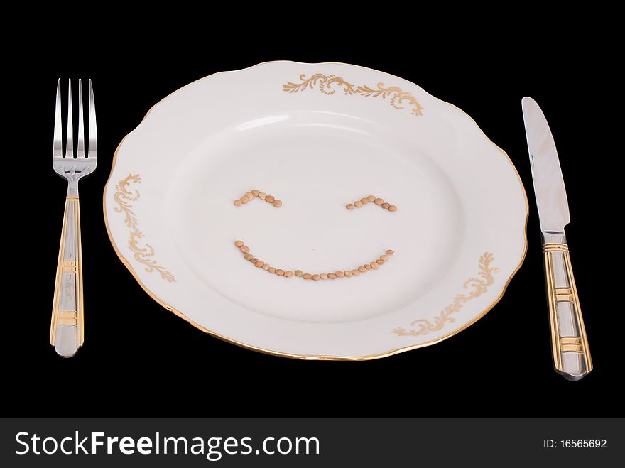 Plate, plug and knife on black background, with clipping paths. On a plate the smilie from lentil is represented. Plate, plug and knife on black background, with clipping paths. On a plate the smilie from lentil is represented