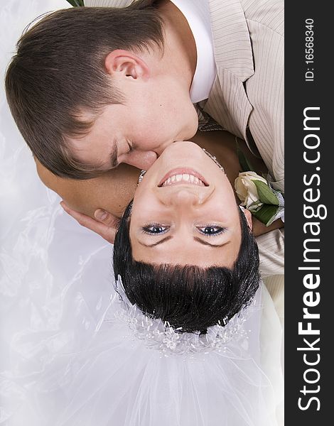 Loving groom and beautiful bride are happy together. A white background.