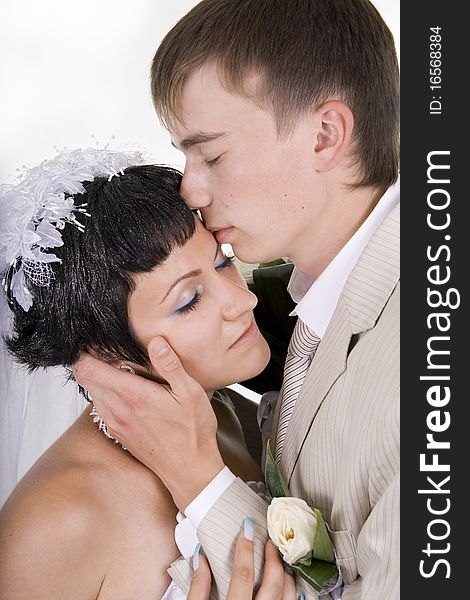 Loving groom and beautiful bride are happy together. A white background.