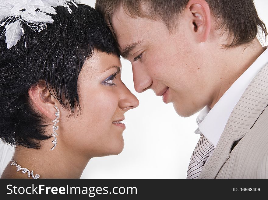 Loving groom and beautiful bride are happy together. A white background.