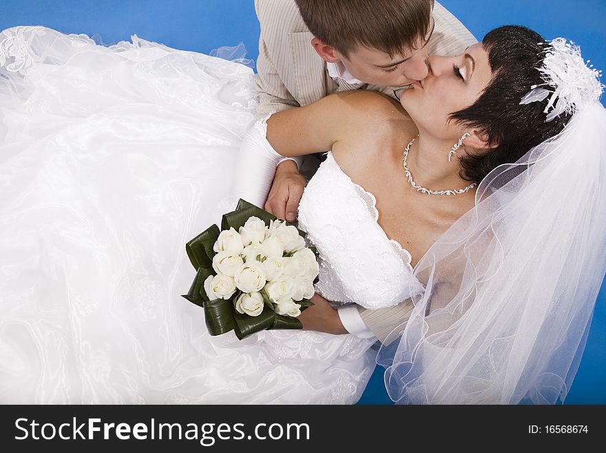 Loving groom and beautiful bride are happy together. Blue background.