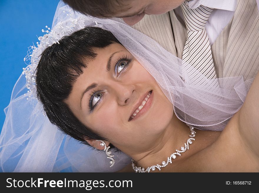 Loving groom and beautiful bride are happy together. Blue background.