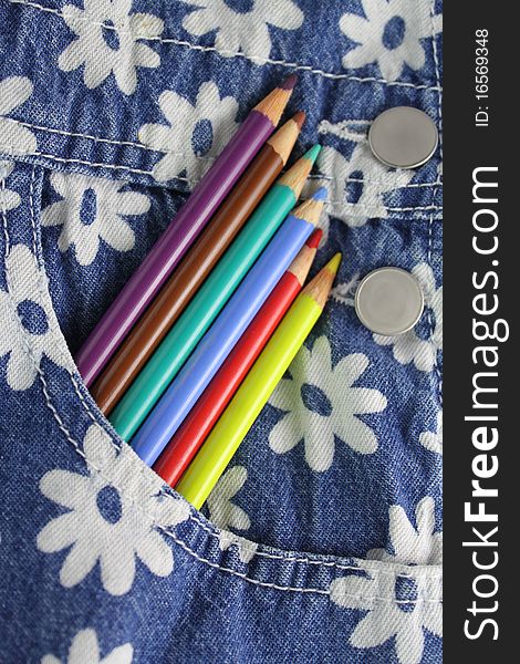 Colored pencils lined up in the pocket of cute denim overalls. Colored pencils lined up in the pocket of cute denim overalls.