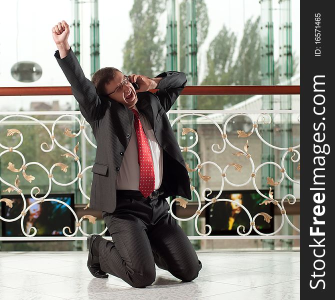 Smiling man with mobile phone on background of glass wall