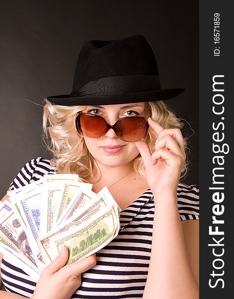 Photo of beautiful young woman of blonde in sunglasses and hat with money in a hand