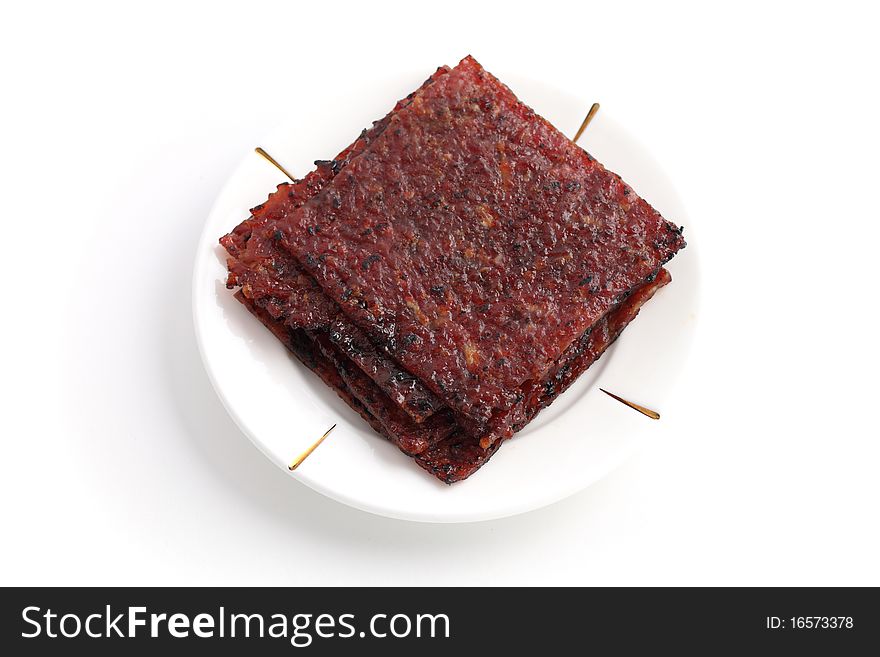 Close up of barbecue meat stacked on white plate isolated over white background.