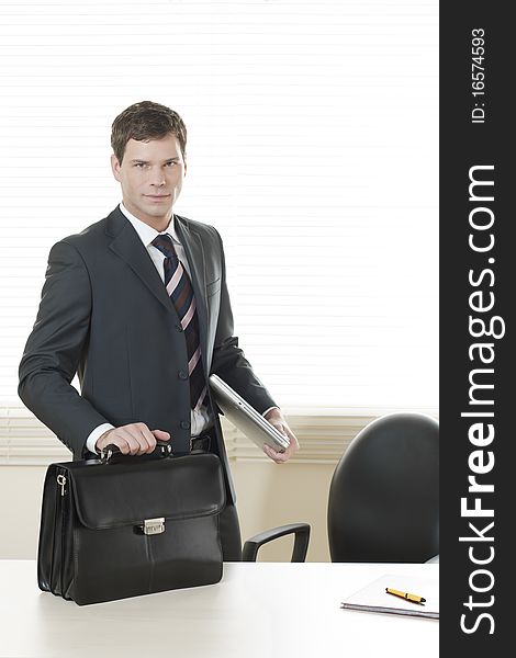 Businessman in his office with briefcase. Businessman in his office with briefcase