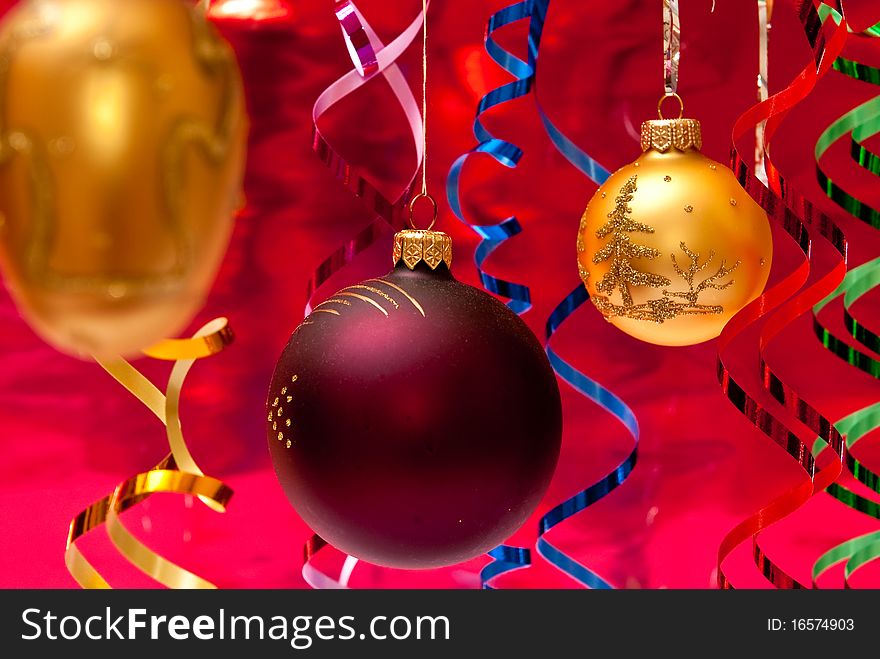 Red christmas ball and colored ribbons. Red background. Red christmas ball and colored ribbons. Red background
