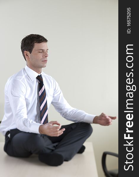 Young businessman meditating on his desk. Young businessman meditating on his desk