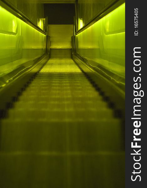 A back-lit green escalator, going down