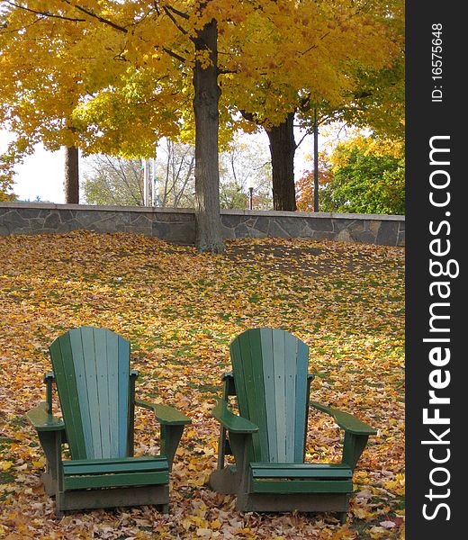 Two chairs sit amongst the fallen leaves giving a welcome to enjoy the foliage. Two chairs sit amongst the fallen leaves giving a welcome to enjoy the foliage.