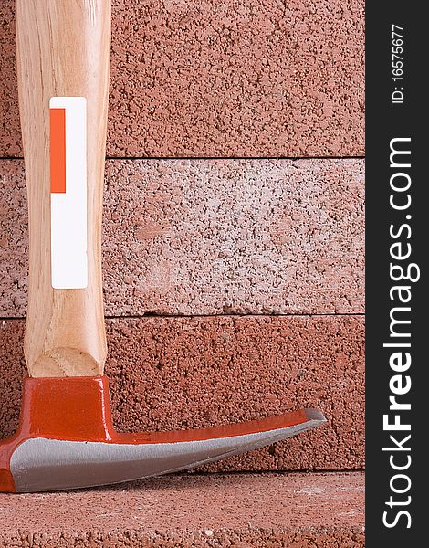 Stonemason's hammer on a background of red bricks.