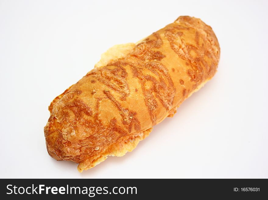 The ruddy long loaf of bread is strewed by cheese isolated on a white background