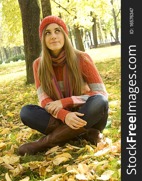 Portrait of a beautiful young woman. Sitting outside in a pile of autumn leaves, smiling, looking up. Portrait of a beautiful young woman. Sitting outside in a pile of autumn leaves, smiling, looking up