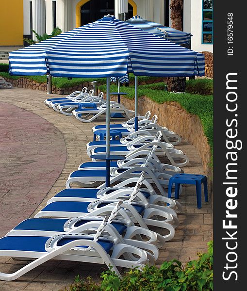 Sun chairs and umbrellas near hotel swimming pool