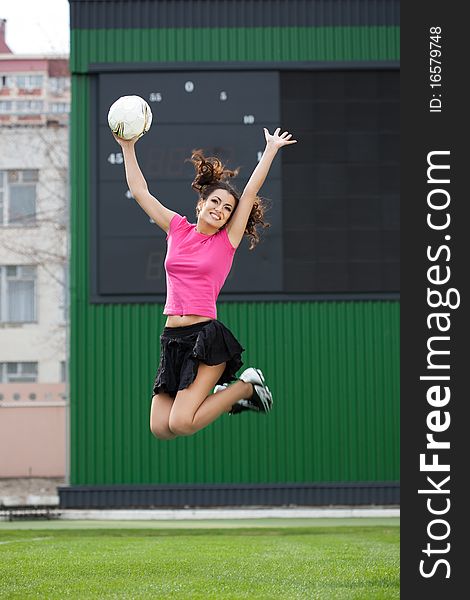 Girl cheerleaders jumping with a soccer ball