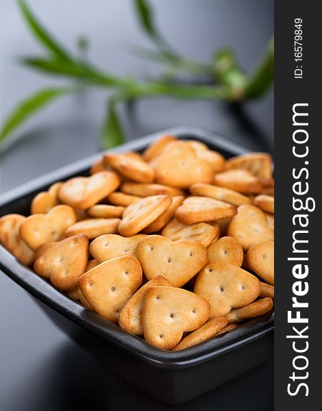 Salted heart shaped crackers in black bowl. Salted heart shaped crackers in black bowl