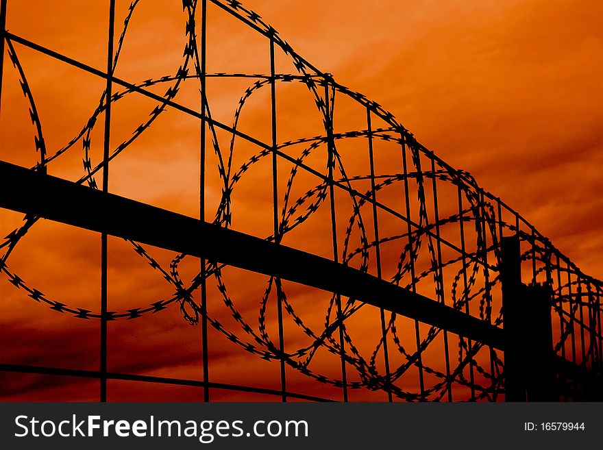 Silhouette of razor wire against a sunset sky. Silhouette of razor wire against a sunset sky