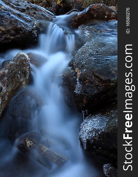 Mountain stream in cold weather and with ice on the rocks