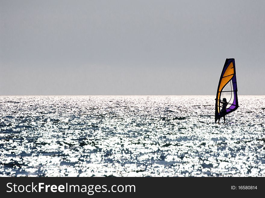 Silhouette of a windsurfer sailing at sunset