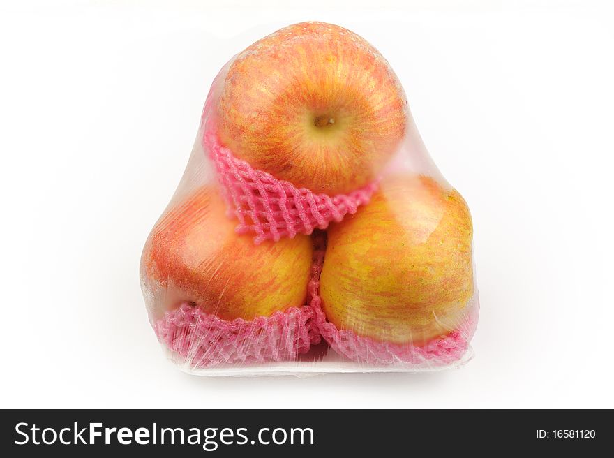 Close up of three apple shipping net on a white surface.