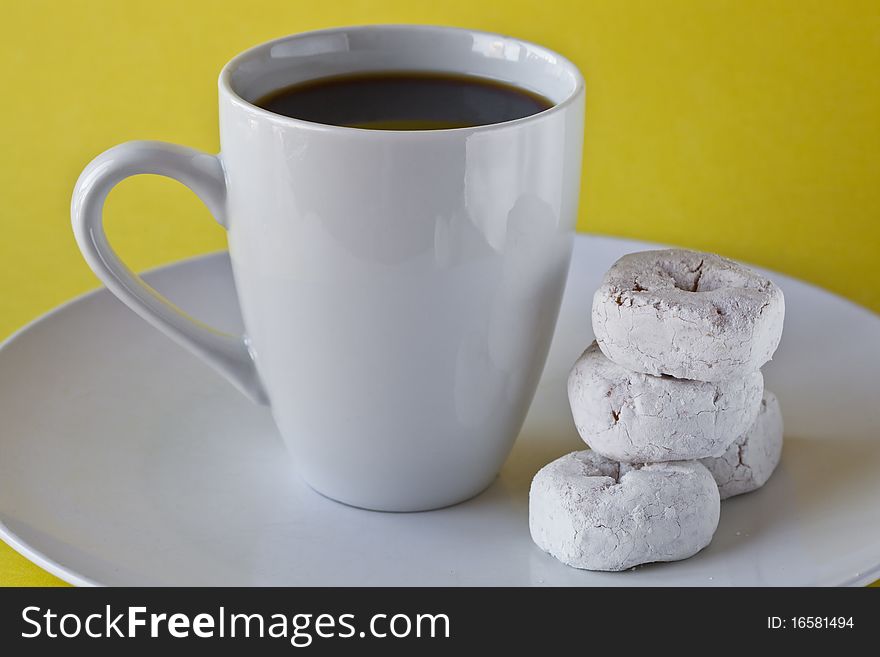 Coffee with donuts on plate with yellow background