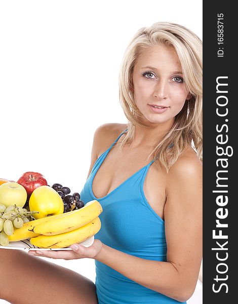 A woman in a blue shirt holding a plate of fruit. A woman in a blue shirt holding a plate of fruit.