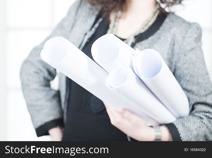 A young business woman in the office holding  some rolls. Close up and focus on the rolls of paper. A young business woman in the office holding  some rolls. Close up and focus on the rolls of paper