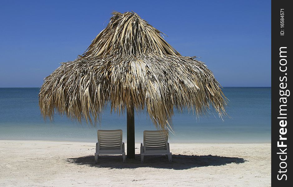 Two chairs and palapa in front of the ocean. Two chairs and palapa in front of the ocean