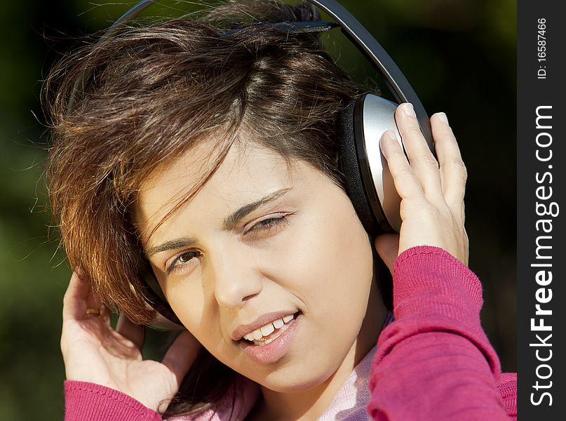 Pretty young girl listening music in the park