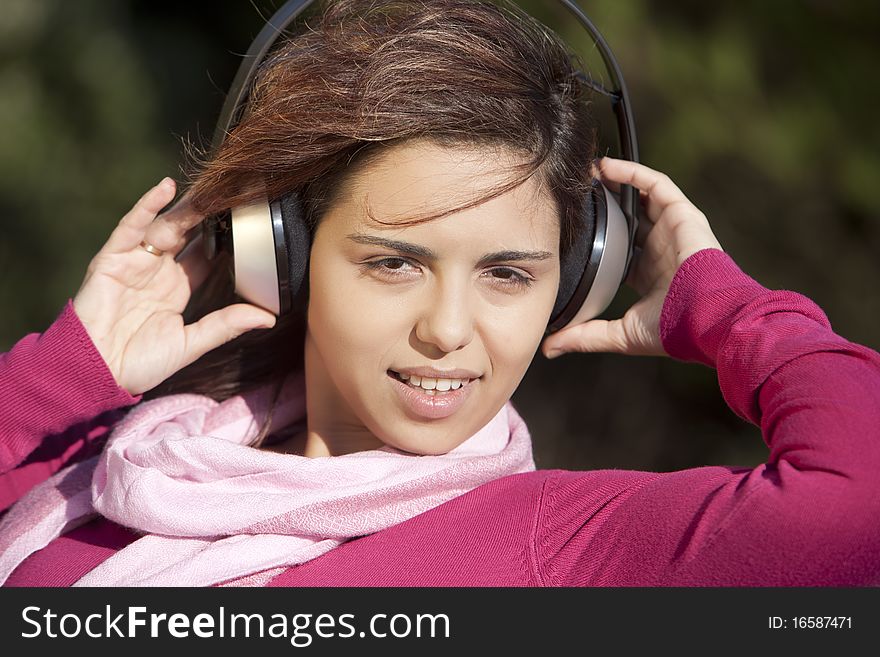 Pretty young girl listening music in the park