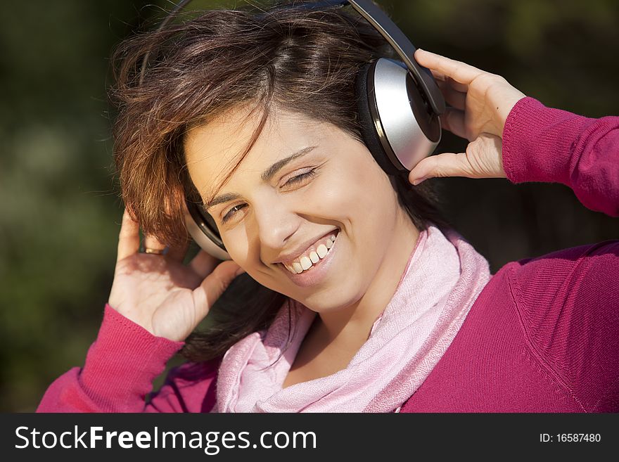 Pretty young girl listening music in the park