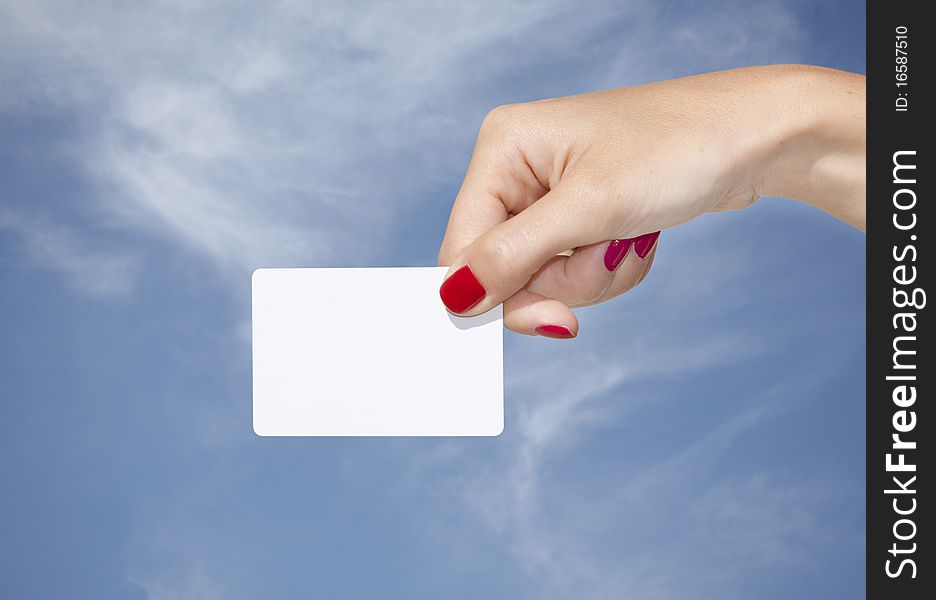 Hand holding an empty business card with a blue sky background