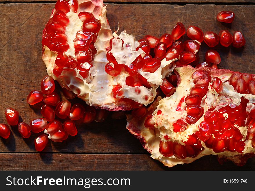 Closeup of cracked  red pomegranate on dark wooden board