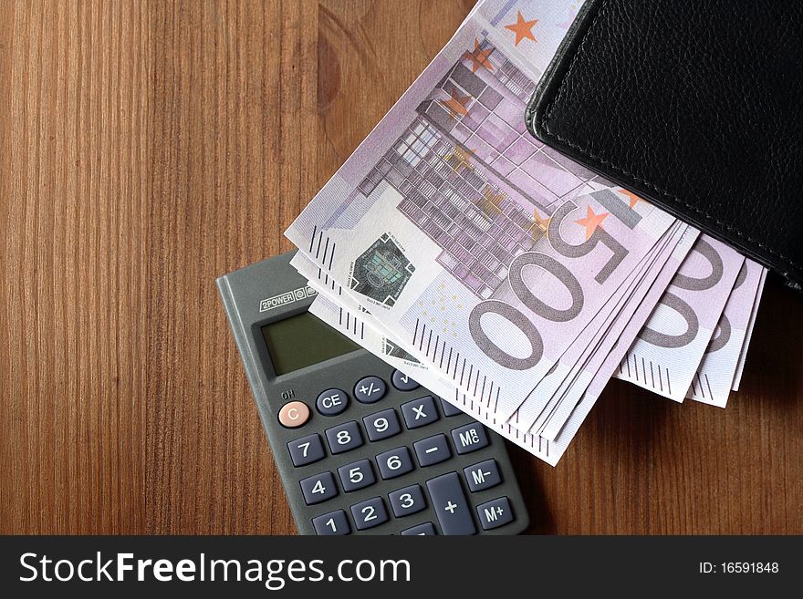 European union currency and calculator on wooden background. European union currency and calculator on wooden background