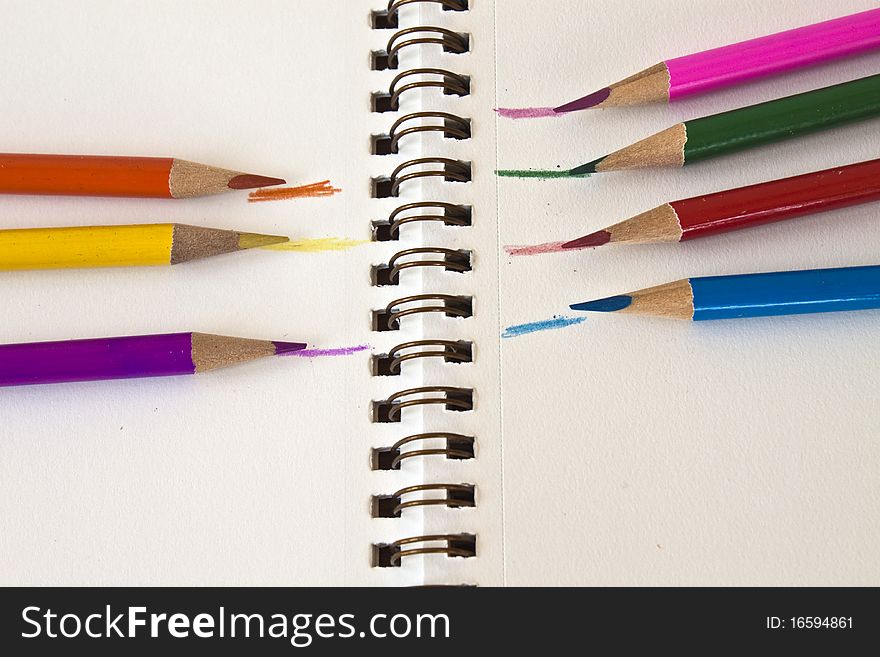 Colored pencils and sketch pad opened showing the spiral spine.