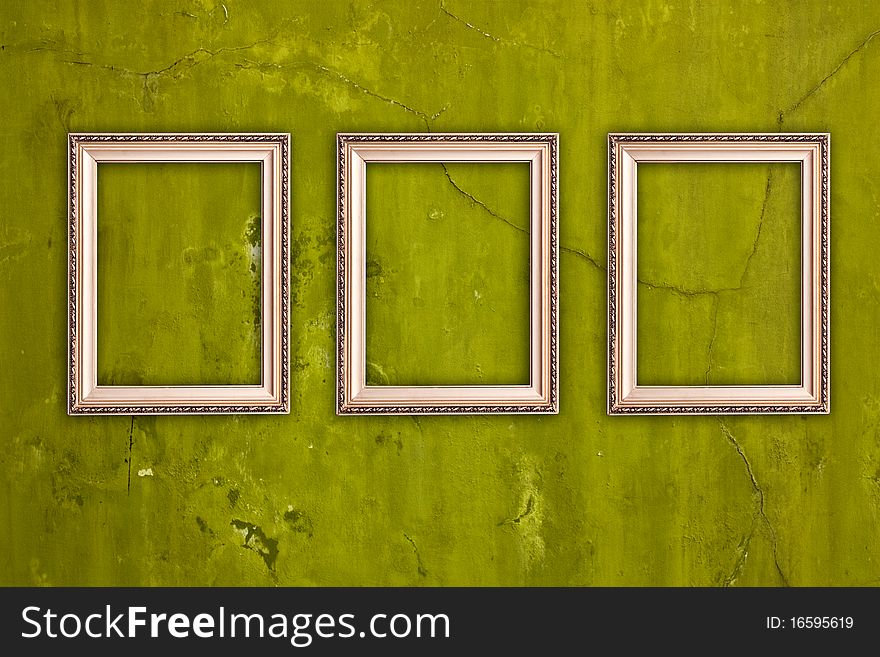 Three blank frames hanging on vintage green cracked wall