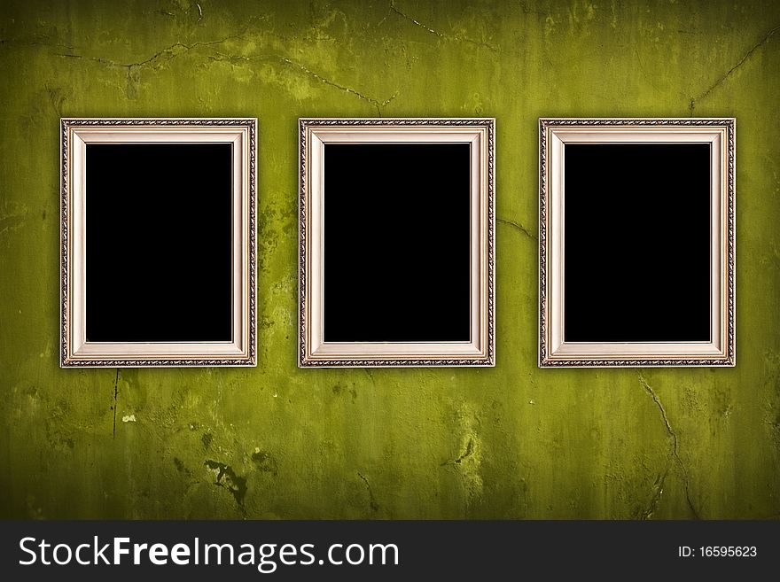 Three blank frames hanging on vintage green cracked wall