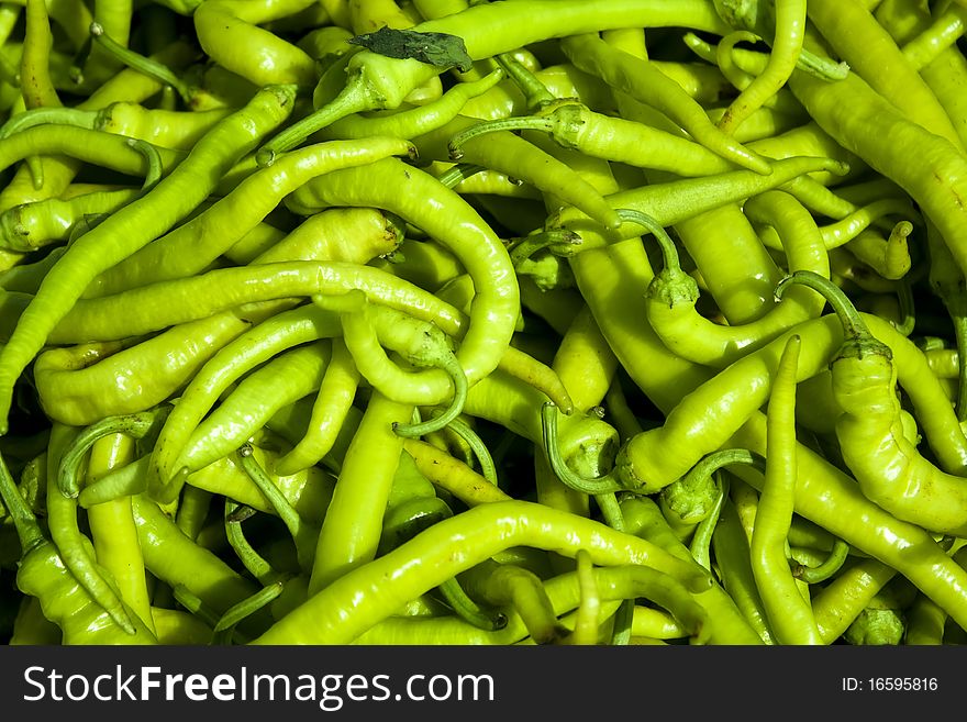 Pile of green pepperoni at the local market.