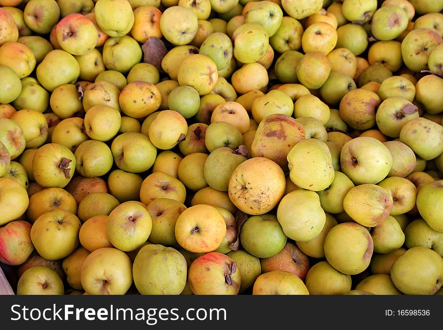 Closeup of multiple yellow apples for sale at an outdoor market.