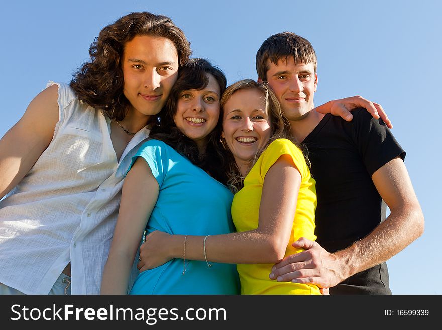 Young people, two girls and two boys, hugged each other and smile