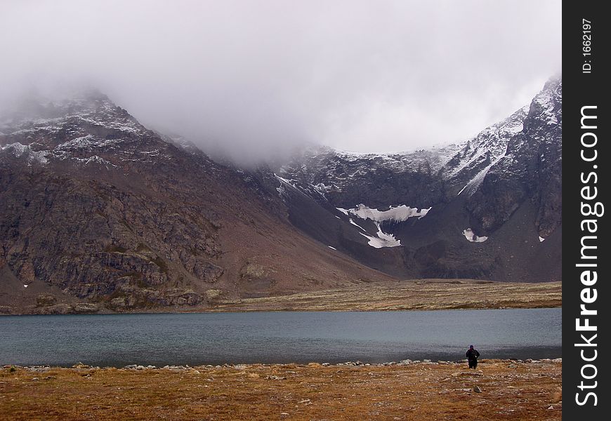 Alpine lake surrounded by knife edged mountain ridge dusted with snow