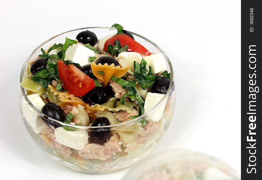 Pasta salad on glass bowl with fetta cheese and olives with soft reflection