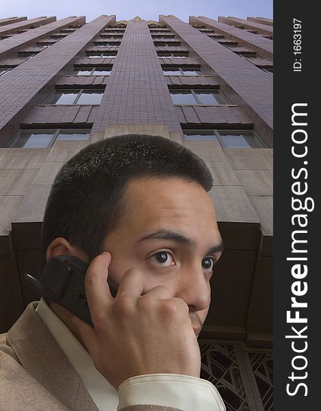 A young hispanic male on cell phone against office building. A young hispanic male on cell phone against office building