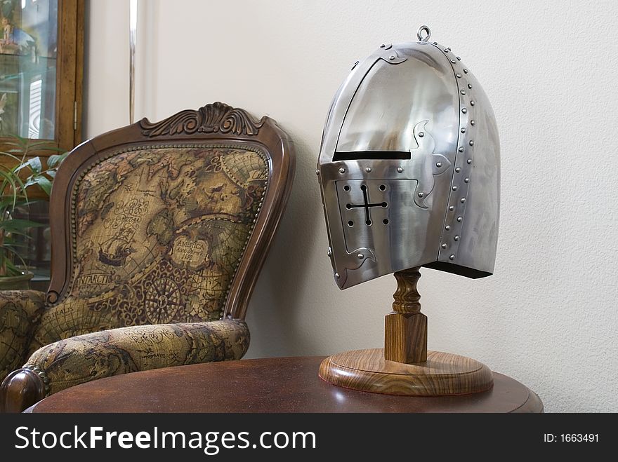 A medieval helmet on a table between chairs