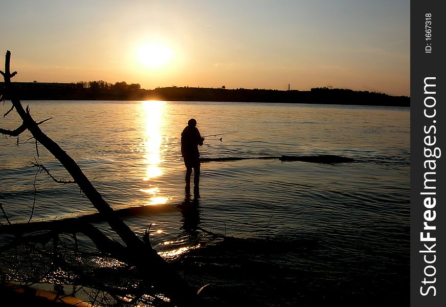 Man fishing at sunset river