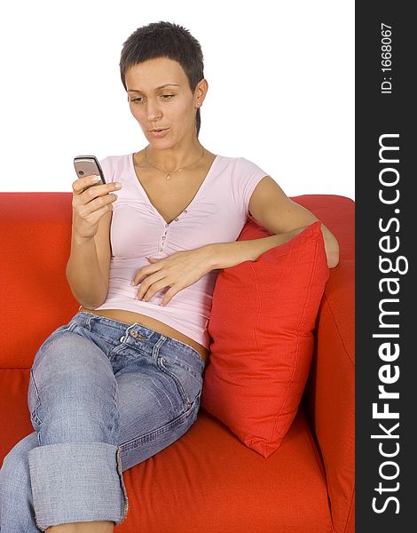 Woman looking at the mobile; sitting on the red sofa. Woman looking at the mobile; sitting on the red sofa